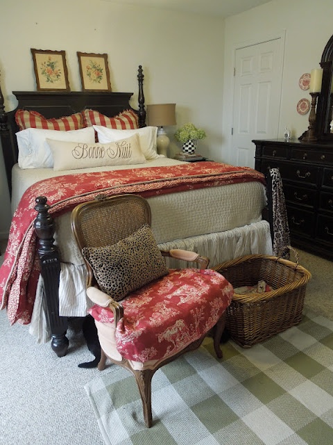 a vintage farmhouse bedroom in black and white, with wicker furniture and a box plus artworks