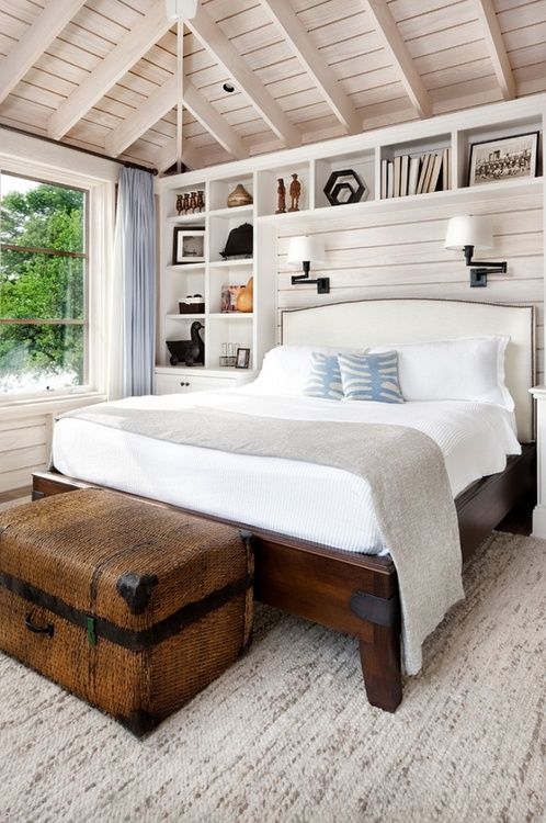 a neutral farmhouse bedroom with an attic ceiling, a wooden bed and a large chest for storage