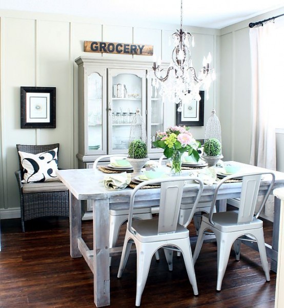 a neutral farmhouse dining area with whitewashed furniture, metal and wicker chairs, a sign and artworks