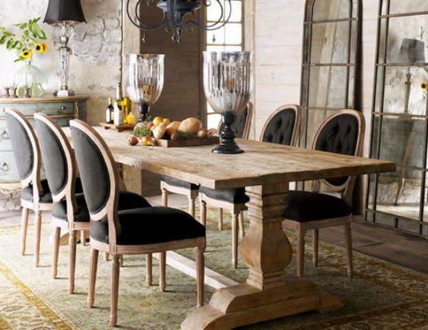 an elegant and formal farmhouse dining area with a wooden table, upholstered chairs, a large metal chandelier and oversized glass urns