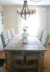 a farmhouse dining room with a shabby chic wooden table, blue upholstered chairs, a rustidc chandelier and wicker shades