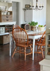 a cozy farmhouse dining space with a wooden table, orange chairs, a large vintage buffet, a vintage chandelier