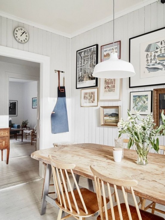 a modern farmhouse dining room with  a chic wooden dining set, a gallery wall and simple white lamps