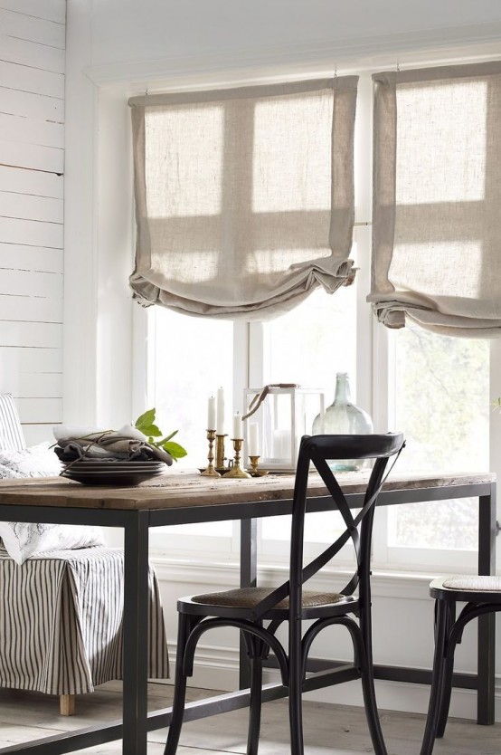 a neutral farmhouse dining space with burlap shades, wood and metal tables and chairs and striped furniture covers