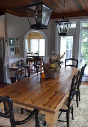 a cozy vintage farmhouse dining room with a wooden table, black painted chars, lanterns and a basket centerpiece