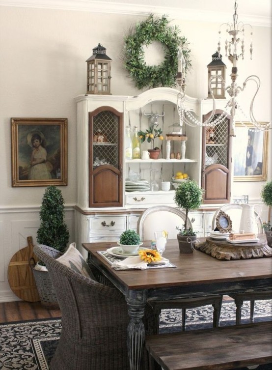 a classic farmhouse dining space with a shabby chic dining set, wicker chairs, a white and brown buffet and beautiful artworks