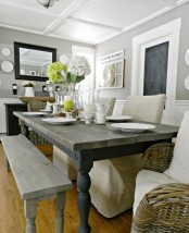 a farmhouse dining space with vintage wooden benches and a table, fabric covered chairs, wicker chairs and a black sideboard
