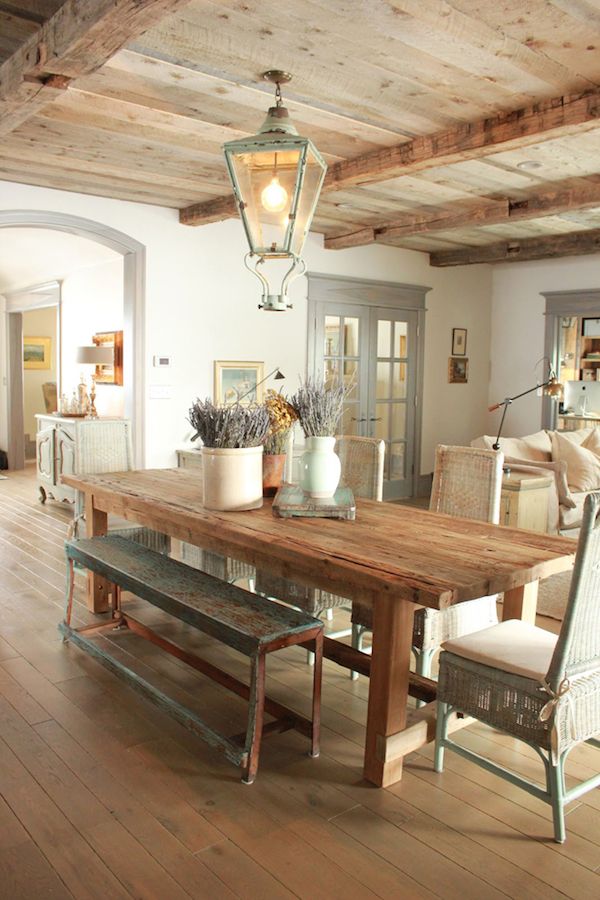 a French farmhouse dining space with a wooden table, patina chairs and benches plus a lantern over the table