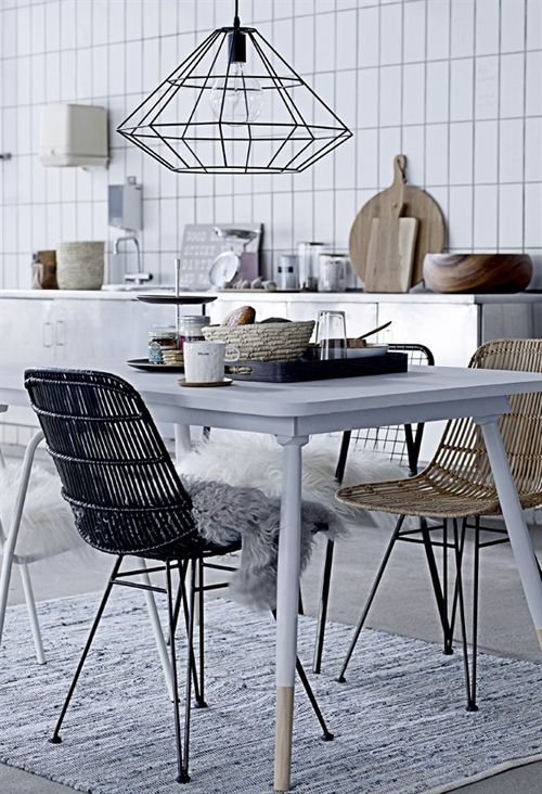 a Nordic dining space with a white dining table, rattan chairs, a geometric pendant lamp and a rug plus faux fur chair covers
