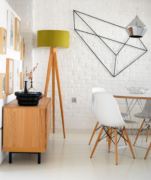 a modern meets Scandi dining table with geometric decor on the wall, a dining table with geo legs, white chairs, a gallery wall and a geometric pendant lamp