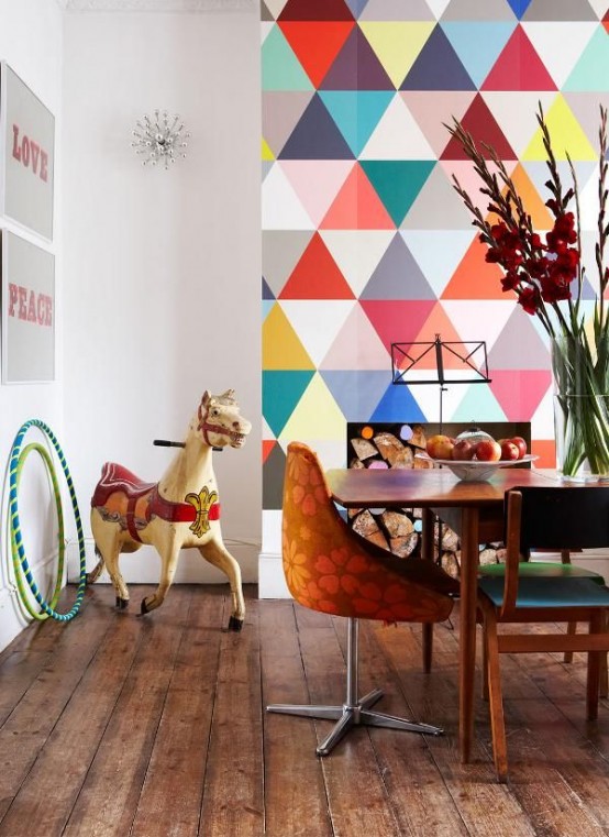 a bold dining room with a colorful geometric accent wall, a stained dining set, some art and a faux fireplace with firewood inside