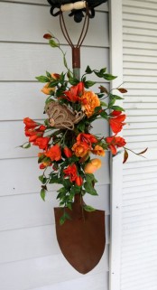 a bright faux bloom decoration with greenery, a burlap bird and a shovel is a nice rustic outdoor decoration