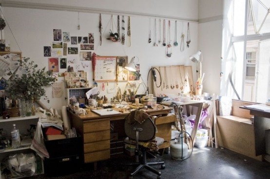 a neutral and light-filled boho chic home office with white walls, a gallery wall with lots of artworks and details, greenery in a pot and some hanging on the wall