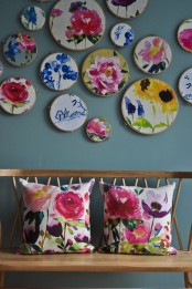 a stained bench with bright floral pillows and an arrangement of embroidery hoops with flowers embroidered is amazing