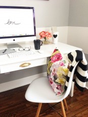 a monochromatic black and white home office and a bold floral pillow to add a touch of color and print to the space