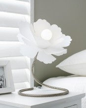 a white flower-shaped table lamp of metal with a large lampshade is a creative addition to a bedroom