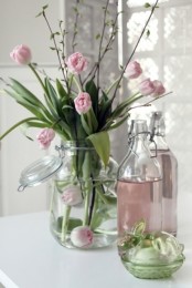 a large jar with a lid, pink tulips and green branches is a pretty modern arrangement for spring