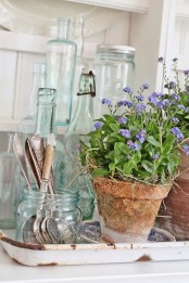 terracotta planters with purple blooms and hay for a slight rustic sprign feel in your space or outdoors, on the porch