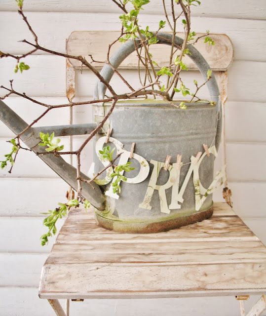 a galvanized watering can with green branches and a SPRING banner is a simple rustic and shabby chic decoration for outdoors