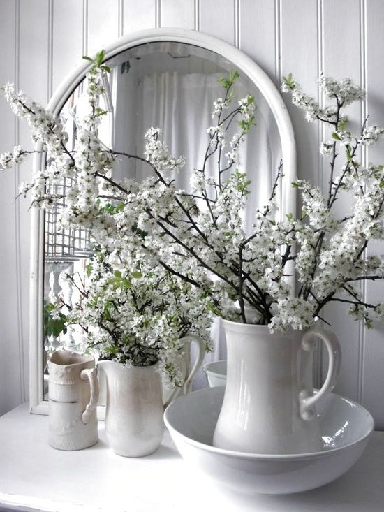white jugs and vases with white blooming branches for a relaxed rustic interior with a vintage feel