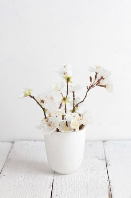 a white vase with white cherry blossom is a lovely and fresh idea that will bring a spring feel and a cool aroma to the space