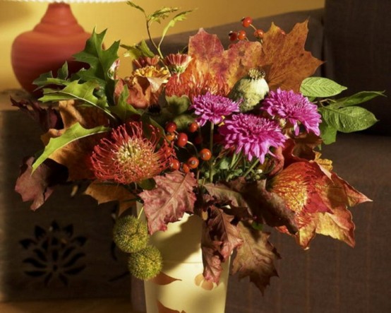 a decadent fall or Thanksgiving centerpiece of pink, burgundy blooms, berries, dark fall leaves is a catchy and chic idea