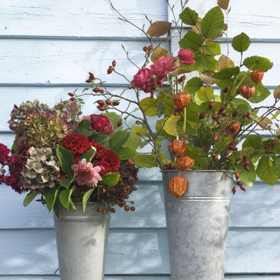 a duo of rustic Thanksgiving centerpieces in buckets, with bold fresh and dried blooms, greenery and seed pods is a very creative idea with a rustic feel