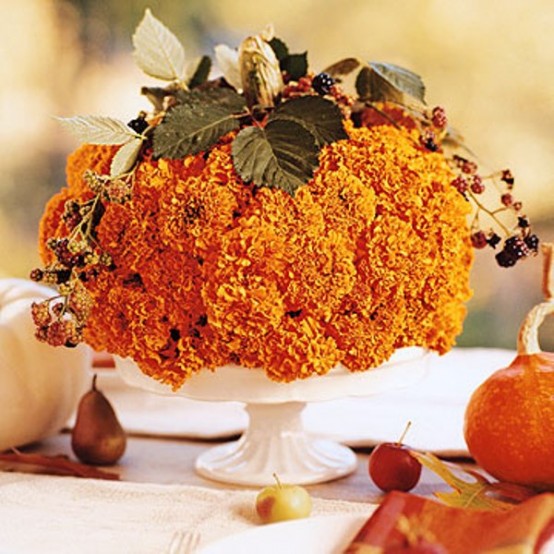 a bold floral arrangement of orange blooms, berries and greenery is a pretty fall or Thanksgiving centerpiece