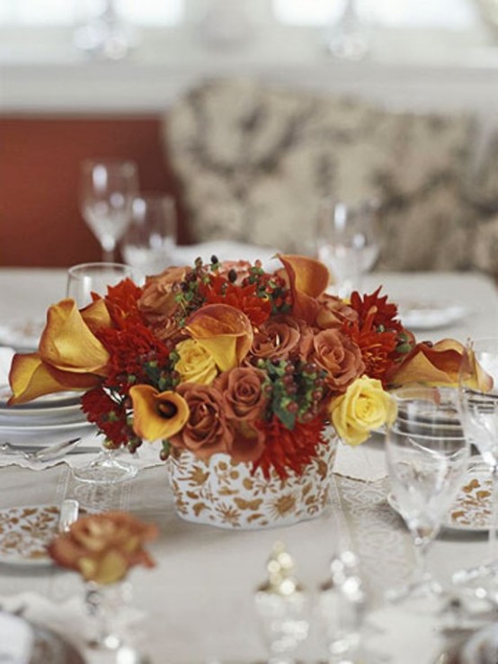 a bold Thanksgiving centerpiece of burgundy, red and yellow blooms and greenery is a cool touch of color to the space