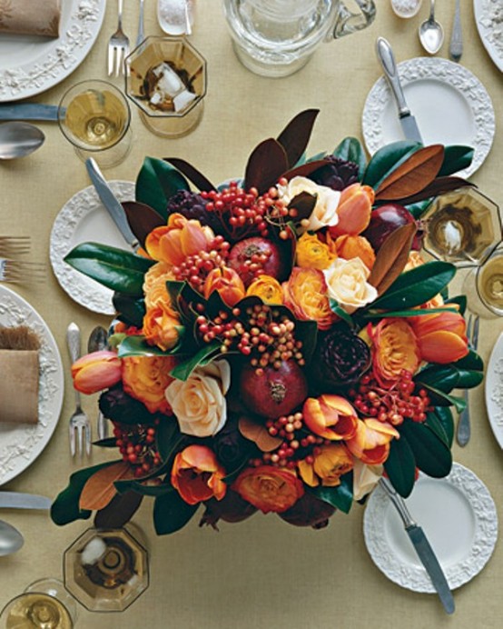 a bold fall or Thanksgiving centerpiece of orange and yellow blooms, berries, foliage and pomegranates is a cool and bold idea