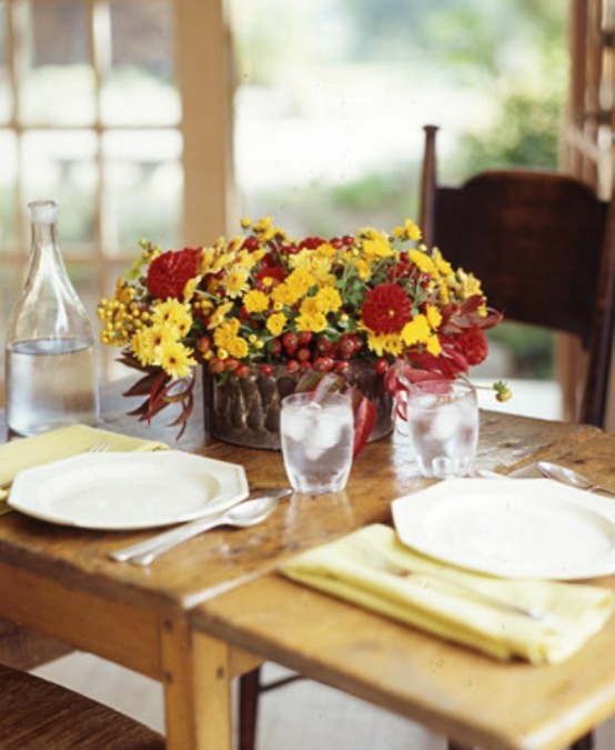 a bright fall or Thanksgiving centerpiece of burgundy and yellow blooms and berries plus some dark foliage is a cool and bold idea