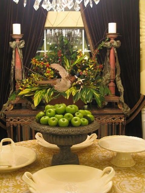 a vintage urn filled with apples and a greenery and bold flower centerpiece with a bird and feathers will give a vintage touch to yourThanksgiving
