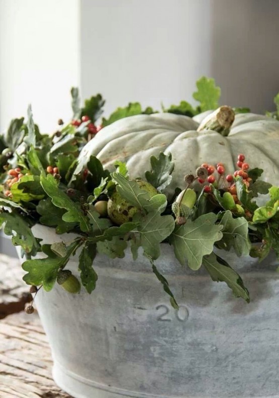 a bucket with greenery, berries and a white pumpkin will make up a cool Thanksgiving centerpiece or decoration