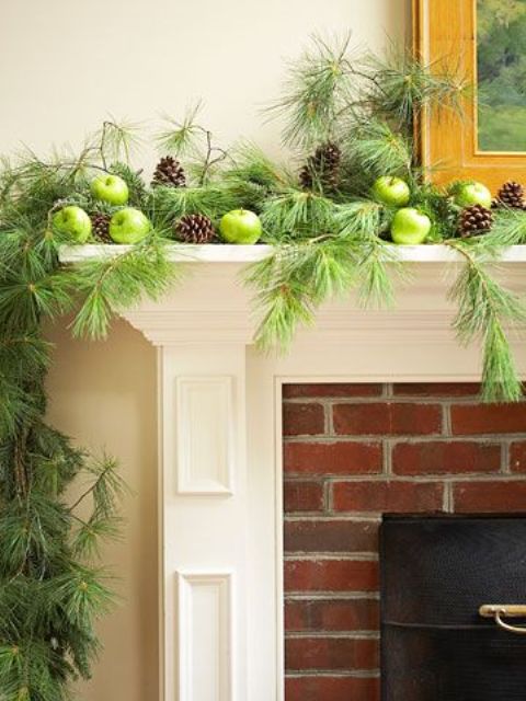 a green Thanksgiving mantel with green apples, fir branches and pinecones is woodland and rustic