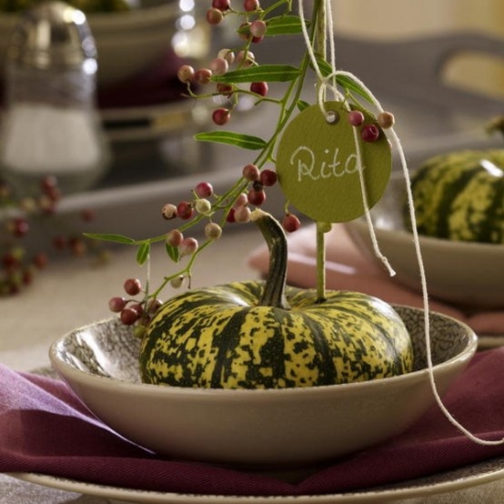 a green pumpkins, berries and a green card plus white porcelain and burgundy napkins make up a cool and stylish Thanksgiving tablescape