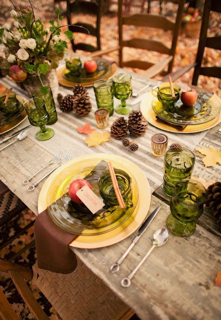 a cozy rustic Thanksgiving tablescape done with greenery touches, green glasses and plates, greenery and white blooms is very beautiful and woodland-like