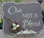 a chalkboard spring sign with white calligraphy and a faux nest with twigs and faux eggs is a classic idea for spring