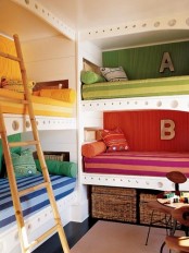 a colorful shared kid’s room with a grene, red, yellow and blue built-in bunk beds, a ladder and colorful and printed pillows