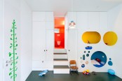 a white kid’s room with a quirky design – a bed and a reading space hidden inside a white unit with colorful circles and sleek storage units around
