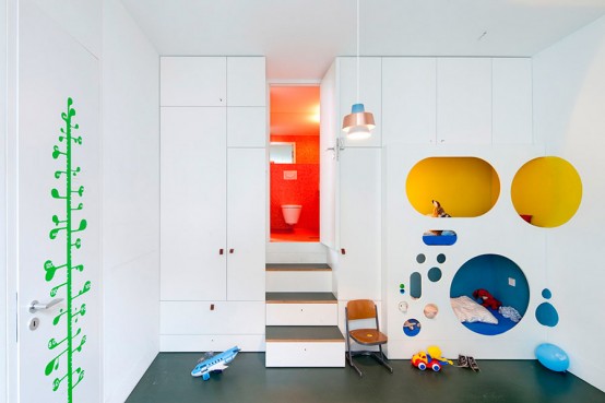 a white kid's room with a quirky design - a bed and a reading space hidden inside a white unit with colorful circles and sleek storage units around