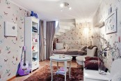 a beautiful and delicate kid’s space with butterfly wallpaper, white furniture – a bed, a storage unit, comfy chairs and lilac and purple textiles