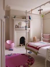 a greige girl’s room with a non-working fireplace, a canopy bed with neutral and fuchsia bedding, a hot pink rug and a sleek pink chair