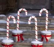 pretty outdoor Christmas decor done with buckets with faux snow and candy canes is a very fun and cool idea