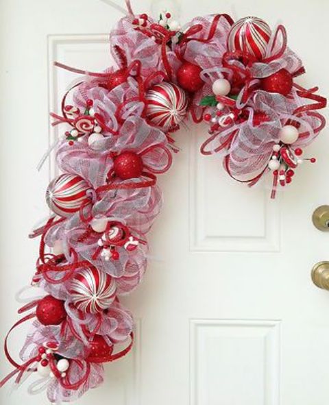 a red and white ribbon and ornament candy cane shaped wreath is a very creative alternative to a usual Christmas wreath