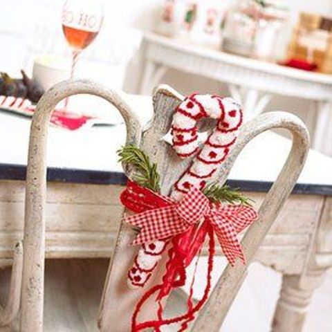 a vintage chair decorated with a knit candy cane and a red bow plus some fir branches is a lovely and cool idea for Christmas