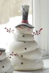 a creative vintage snowman of clay, in a top hat and with berry branches as arms is a lovely and pretty vintage decoration to rock