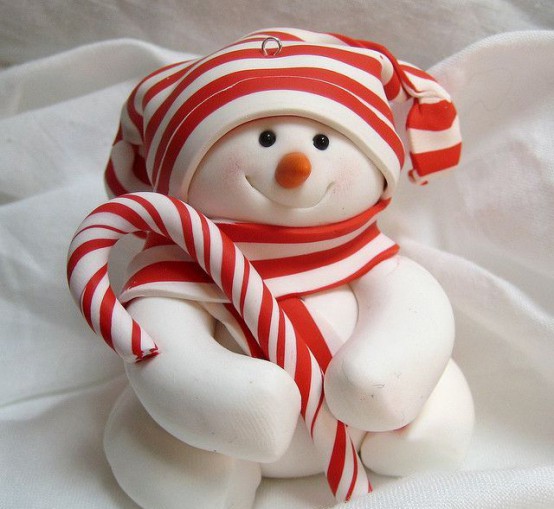 a pretty white snowman decoration with a candy and a striped hat and scarf that match and make the piece look bolder