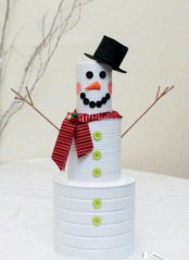 a snowman of tin cans, colorful buttons, a scarf and twigs is a great Christmas craft for your kids, make it together with them