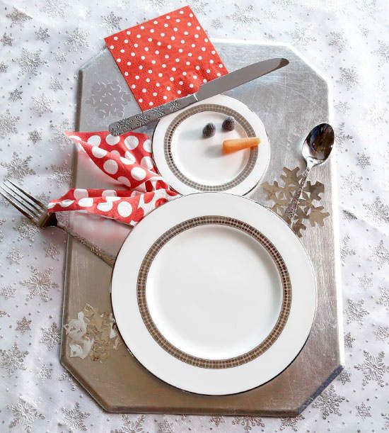 a pretty Christmas place setting with a silver board, a snowman of plates and some bright touches is a cool idea for a modern winter wedding