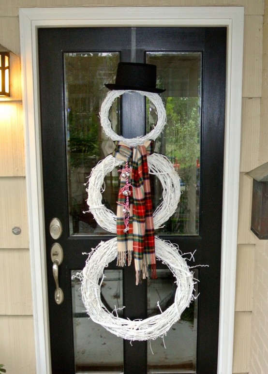 a white snowman made of white wreaths, a plaid scarf and a black top hat is a cool alternative to a usual Christmas wreath on your door